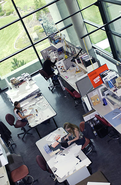 A overhead view of a group workspace with multiple large tables and glass walls.